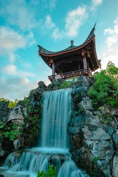 Fototapeta Vertical shot of the pagoda and waterfall in Fukushuen Chinese Garden in Naha Okinawa, Japan