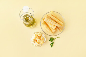 Plate with cut and whole canned baby corn cobs on yellow background