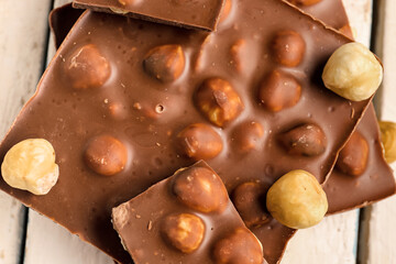 Sweet tasty chocolate with nuts on  light wooden background, closeup