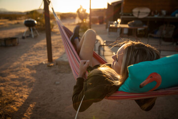 This image shows a woman relaxing in a hammock on a sunny desert day. 