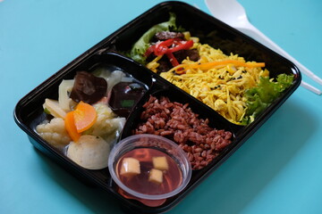 healthy food bento with brown rice, yellow shredded chicken, vegetable soup, tempeh and fruit jelly. For diet weight loss program. healthy lunch menu in a plastic container. catering menu diet. 