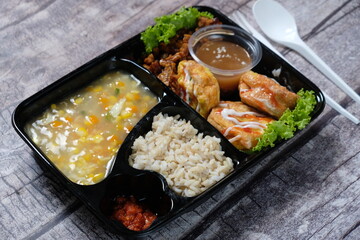 healthy food bento with brown rice, omelette, vegetable corn soup, tempeh and fruit jelly. For diet weight loss program. healthy lunch menu in a plastic container. catering menu diet. 