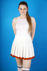 Beautiful sporty woman with long hair is wearing a white tennis dress and stockings in studio