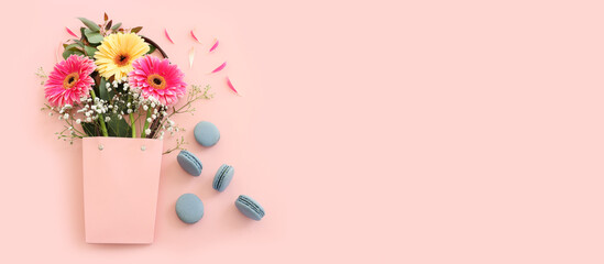 Top view of blue macaron or macaroon and flowers over pastel pink background. Flat lay