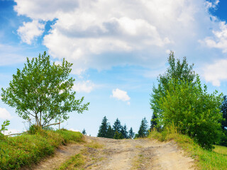 lane through grassy meadow. green hills rolling in to the distance. blue sky above the distant mountain ridge on the horizon. rural tourism in summer. explore countryside of ukraine