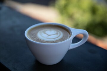 Decprated cappuccino cup on black fence surface with blur background