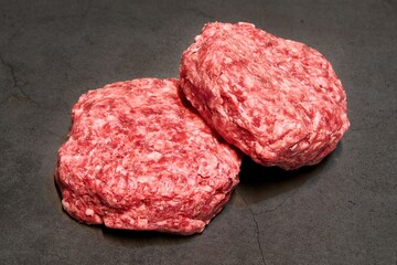 Two pieces of hamburger patty on a gray background