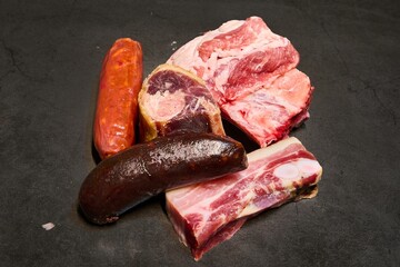 Top view of raw beef and pork meat and sausages on a gray background