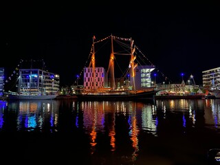 Fototapeta na wymiar Nachtzauber am Bremerhaven: Das verträumte alte Boot und die reflektierenden Lichter