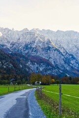 Fototapeta premium Landscape view of the narrow road in the Alps mountain range with autumn trees on the rocks