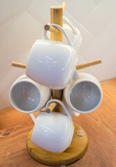 Ceramic cups hang on a wooden stand. (Shallow depth of field)