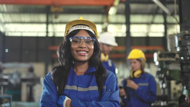African Young woman worker in protective uniform operating machine at factory Industrial.People working in industry.Portrait of Female Engineer looking camera at work place.