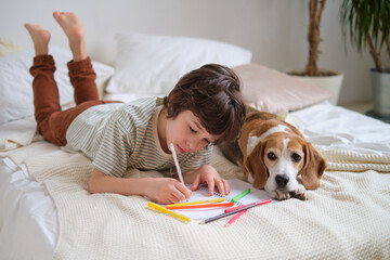 young boy engrossed in drawing with colorful pencils