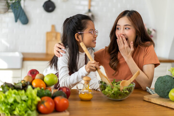 Portrait of enjoy happy love asian family mother with little asian girl daughter child having fun help cooking food healthy eat together with fresh vegetable salad ingredient in kitchen