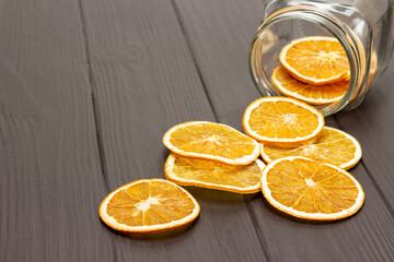 Slices of dried orange are scattered from a glass jar on the table.