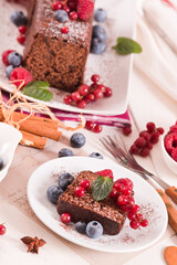 Chocolate sponge cake with fresh fruit on white dish.