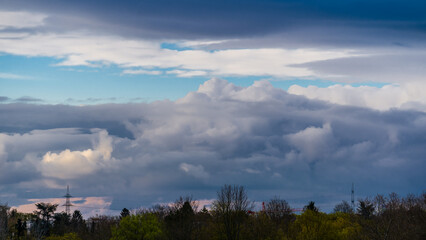 Panorama with big dark clouds over trees and power lines