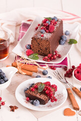 Chocolate sponge cake with fresh fruit on white dish.