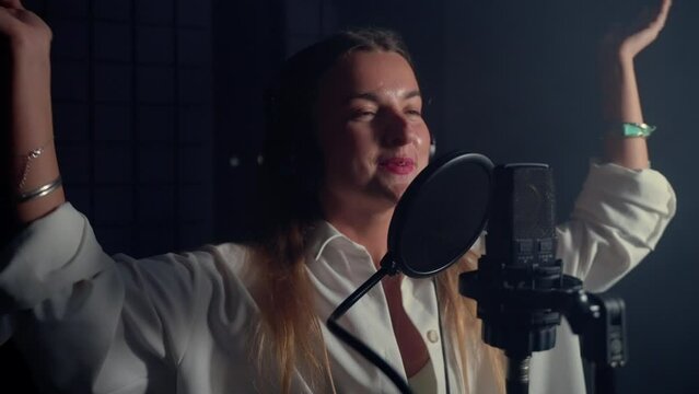 professional voice actress dubbing and singing in isolation booth of modern sound recording studio