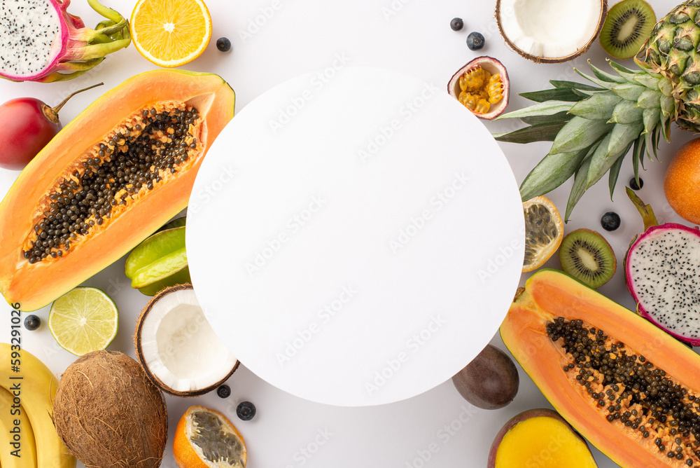 Wall mural Transport yourself to a tropical island concept. Dragon fruit, kiwi, papaya, pineapple, orange, lime, passion fruit, carambola and coconut on white backdrop and an empty circle for text