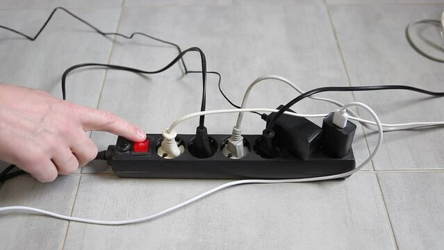 Large electrical power strip with many connected devices. Switching the button on the surge protector on and off. Looped video.