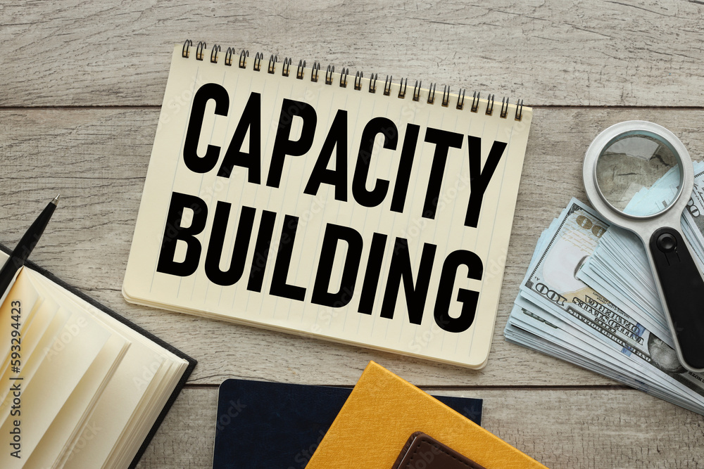 Aufkleber capacity building . business concept. open notepad with text near banknotes on the table