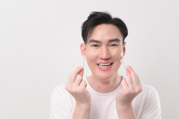 Fototapeta premium Young smiling man holding invisalign braces over white background studio, dental healthcare and Orthodontic concept...