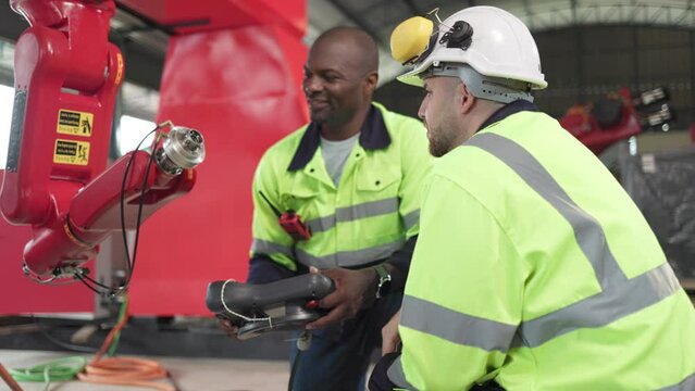 Factory worker working with adept robotic arm in a workshop . Industry robot programming software for automated manufacturing technology .