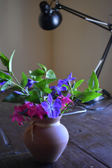 jarrón con flores sobre una mesa con una lampara