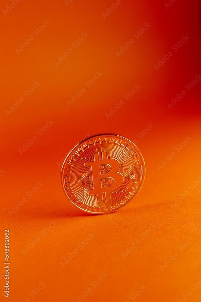 Poster vertical shot of a bitcoin isolated on an orange gradient background
