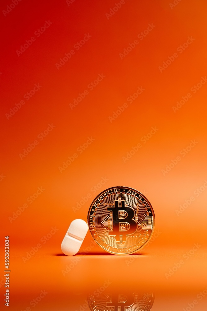 Poster vertical shot of a bitcoin and a pill isolated on an orange gradient background