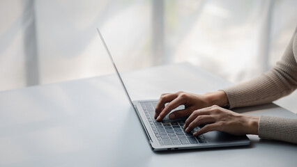 Person typing on laptop keyboard, businessman working on laptop, he is typing messages to colleagues and making financial information sheet to sum up the meeting.