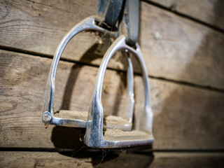 Stirrups hanging against barn wall