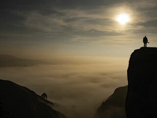 Cloud inversion peak with tree and man in silhouette during sunset