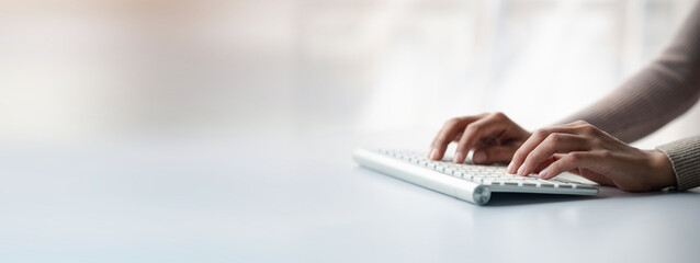 Person typing on a computer keyboard, businessman is working in a startup company's office, he is typing messages to his colleagues and making financial documents summarizing the meetings. Copy space.
