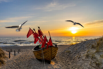 sunset on the beach in usedom with seagulls and fishing boat