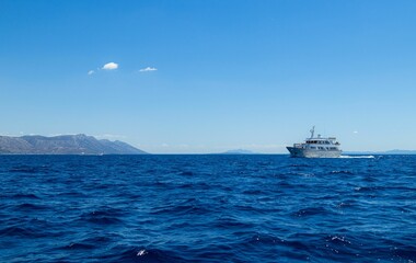 Scenic shot of the water surface of a sea in Croatia with an island and a ship on the background