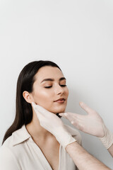 Facebuilding. Doctor examines beauty face of woman. Consultation with plastic surgeon on white...