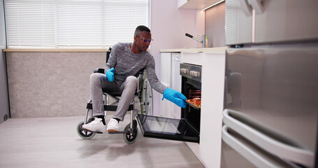 Disabled Man Using Microwave Oven For Baking