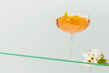 Wine glass of natural apple cider with mint and apple blossoms on glass shelf on blue background. Elegant glass with summer refreshing fermented low-alcohol fruit drink. low angle view, copy space
