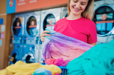 Young beautiful woman washes and dries clothes in the laundry
