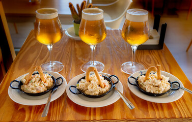 Tapas de ensaladilla rusa con copas de cerveza