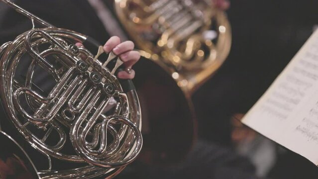 A slow motion video of a French horn player playing their instrument during a live performance