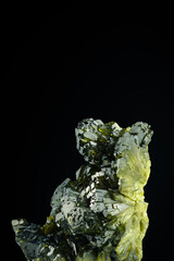 epidote green crystals on black background. macro detail isolated . close-up rough raw unpolished semi-precious gemstone.
