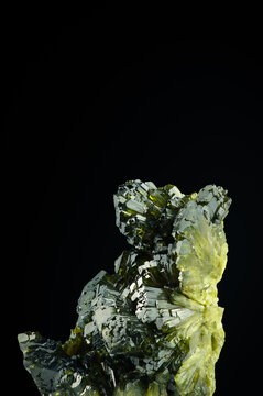 epidote green crystals on black background. macro detail isolated . close-up rough raw unpolished semi-precious gemstone.