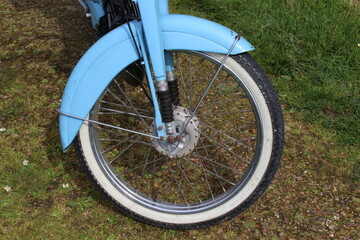 Roue de mobylette ancienne bleue en gros plan avec pneu noir et blanc