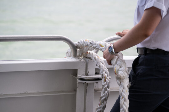 Female hands holding rope on a boat ready to tie the boat to the port. Selective focus on the rope.