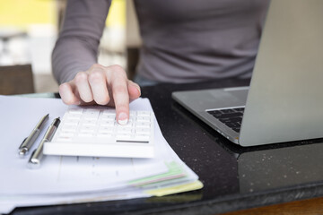 Woman working with calculator and laptop computer. Savings, finances and economy concept. Accounting analyst calculate break even point by using financial report for banking investment.