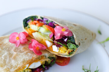 Wrap filled with mixed greens, salad and pink flowers