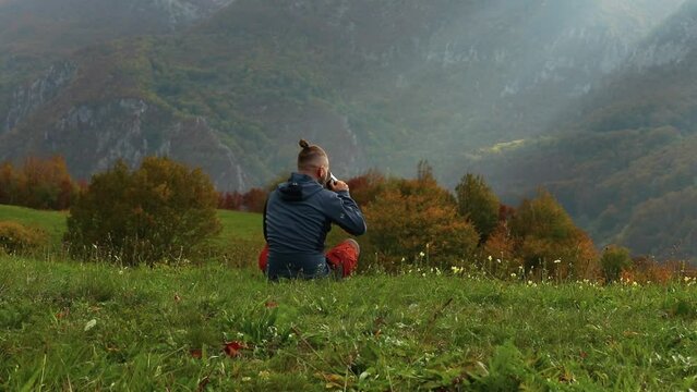 Hiker with a manbun enjoying the serenity of the picturesque mountain view and having a tea